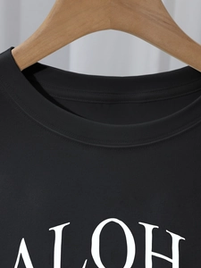 Close-up of the crew neck collar and ALOHA letter print on a black cotton t-shirt