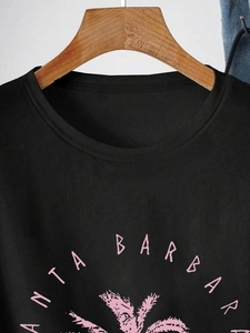 Close-up of pink Santa Barbara text and palm tree print on black cotton t-shirt