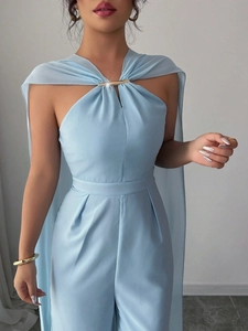 Eleganter hellblauer Neckholder-Jumpsuit mit goldenem Metallbesatz und wehendem Cape