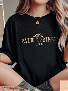 Loose black crew neck T-shirt with golden Palm Springs print and sun graphic design