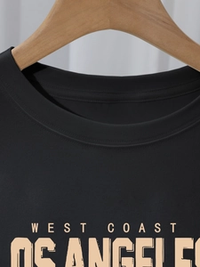 Detail of West Coast Los Angeles print on a black cotton t-shirt hanging on a wooden hanger