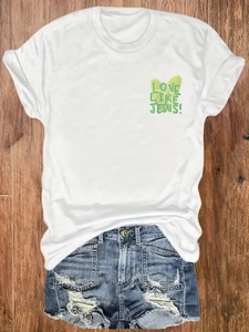T-shirt blanc en coton avec imprimé Love Like Jesus posé sur un sol en bois sombre