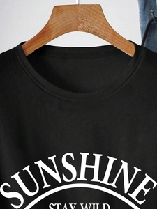 Détail du lettrage blanc Sunshine Stay Wild sur un t-shirt noir à col rond