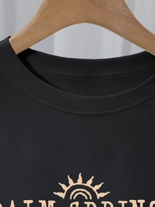Detail of Palm Springs sun graphic and double-needle neckline on a black cotton T-shirt