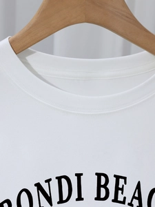 White cotton crew neck T-shirt featuring a Bondi Beach print on a wooden hanger