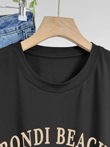 Women's black crew neck T-shirt with vintage Bondi Beach print on a wooden hanger