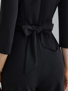 Close-up of elegant black jumpsuit showing the stylish back waist bow tie detail