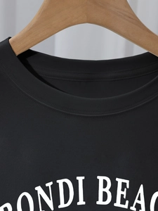 Close-up of ribbed crew neck and Bondi Beach white letter print on black cotton T-shirt
