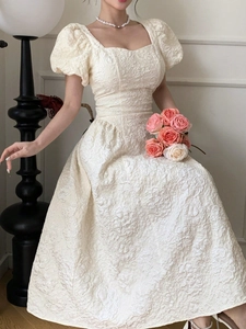 Détail du tissu jacquard à fleurs crème élégant sur la robe vintage à manches bouffantes