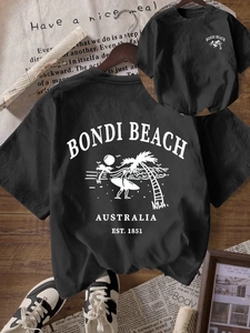 Black Bondi Beach graphic tee with palm trees and retro surfboard print on wooden floor