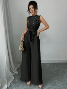 Combinaison élégante noire sans manches à col perlé et taille ceinturée avec nœud chic