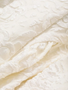 Détail macro du tissu jacquard floral 3D blanc crème avec textures en relief élégantes