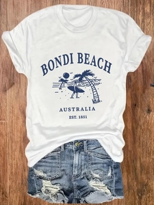 T-shirt Bondi Beach blanc pour femme avec short en jean sur fond en bois naturel
