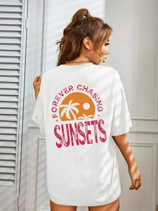 Close-up of white T-shirt back featuring a sunset palm tree graphic and sunset text