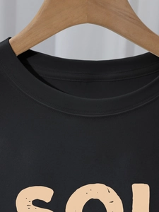 Détail macro du col renforcé à double aiguille sur t-shirt noir en coton avec imprimé