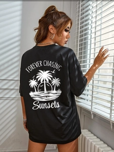 Close-up of black oversized t-shirt featuring coconut trees and sunset back print