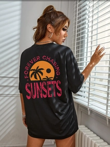 Detail of black oversized T-shirt with sunset palm tree print on the back and text