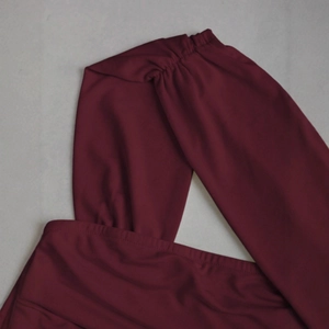 Détail du tissu en maille extensible bordeaux avec un design d'épaule plissée torsadée