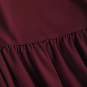 Gros plan sur la texture plissée du tissu bordeaux d'une robe trapèze élégante sans manches