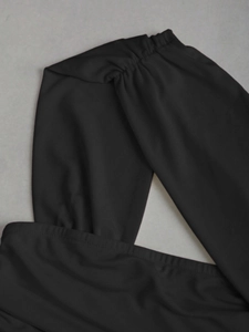 Détail de la robe noire froncée montrant la texture du tissu élastique et les coutures croisées