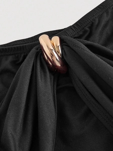 Detail of elegant black V-neck dress featuring a rose gold metal ring buckle and pleated fabric