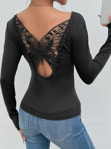 Détail du dos nu avec une grande broderie papillon en dentelle sur un haut noir ajusté