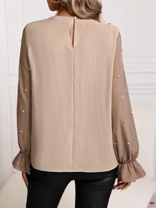 Détail des boutons perle sur manches cloche et ouverture goutte de la blouse