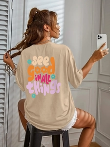 Detail of the oversized beige T-shirt featuring a colorful back graphic and artistic text