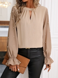 Détail de la blouse kaki élégante avec manches lanterne ornées de perles et de volants
