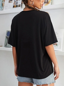 Back view of woman in loose black cotton T-shirt with light blue denim shorts