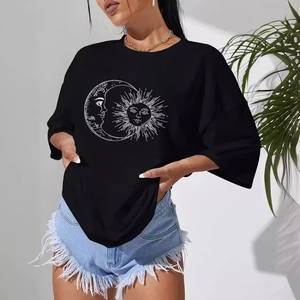 Women's loose black sun and moon graphic T-shirt paired with denim shorts in a modern setting