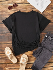 Flat lay of black cotton t-shirt with side knot detail and dark grey jeans on wood floor