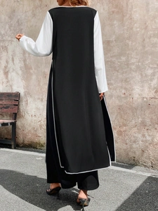 Detail of the high side slit on the black and white contrast long top and trousers set