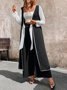 Detail of color-block long vest and wide-leg pants set with side slits and waist tie