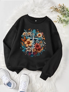 Détail d'un sweat noir à fleurs avec croix et texte faith sur un tapis moelleux blanc