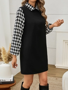 Detail of elegant dress showing houndstooth pattern collar and lantern sleeves on a black base