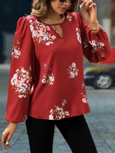 Detail der eleganten Laternenärmel und des Blumendrucks auf einer weinroten Damenbluse