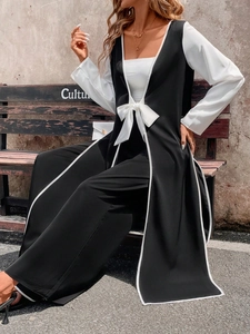 Detailed view of women's long black coat with white piping and waist tie bow detail