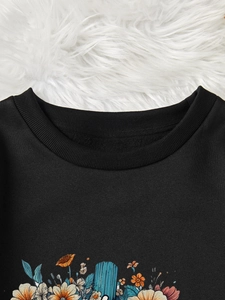 Détail du col rond côtelé et de l'imprimé floral coloré sur le sweat-shirt noir