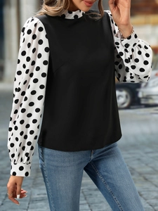 Close-up of contrast polka dot balloon sleeves and elegant high collar on black blouse