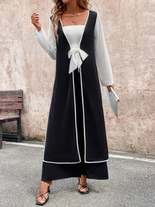Detail of contrast two-piece long set featuring a white bow tie and black side slit trousers