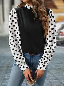 Detailed view of mock neck and polka dot puff sleeves on a chic black blouse