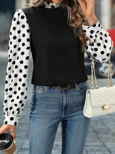 Detail of elegant high neck blouse featuring black bodice and white polka dot sleeves