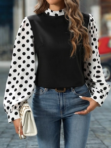Detail of elegant black blouse with white polka dot puff sleeves and high neck collar
