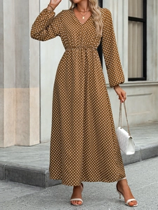 Detail of V-neck long-sleeve maxi dress with white polka dots on brown fabric