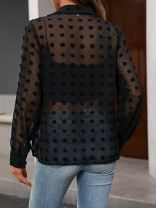 Détail de la texture en tulle à pois suisse au dos d'un chemisier noir transparent
