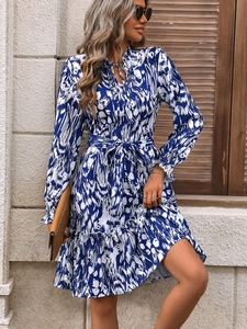 Detailed shot of elegant blue floral dress featuring bell sleeves and a waist belt tie
