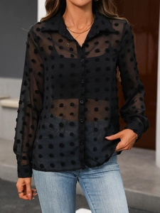 Détail d'un chemisier noir transparent à pois suisses avec col classique et boutonnage