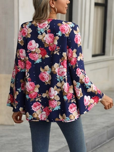 Detail of dark blue floral shirt featuring pink roses and elegant bell sleeves in outdoor light
