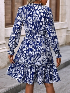 Detail of elegant blue and white print dress featuring layered ruffle hem and belted waistline
